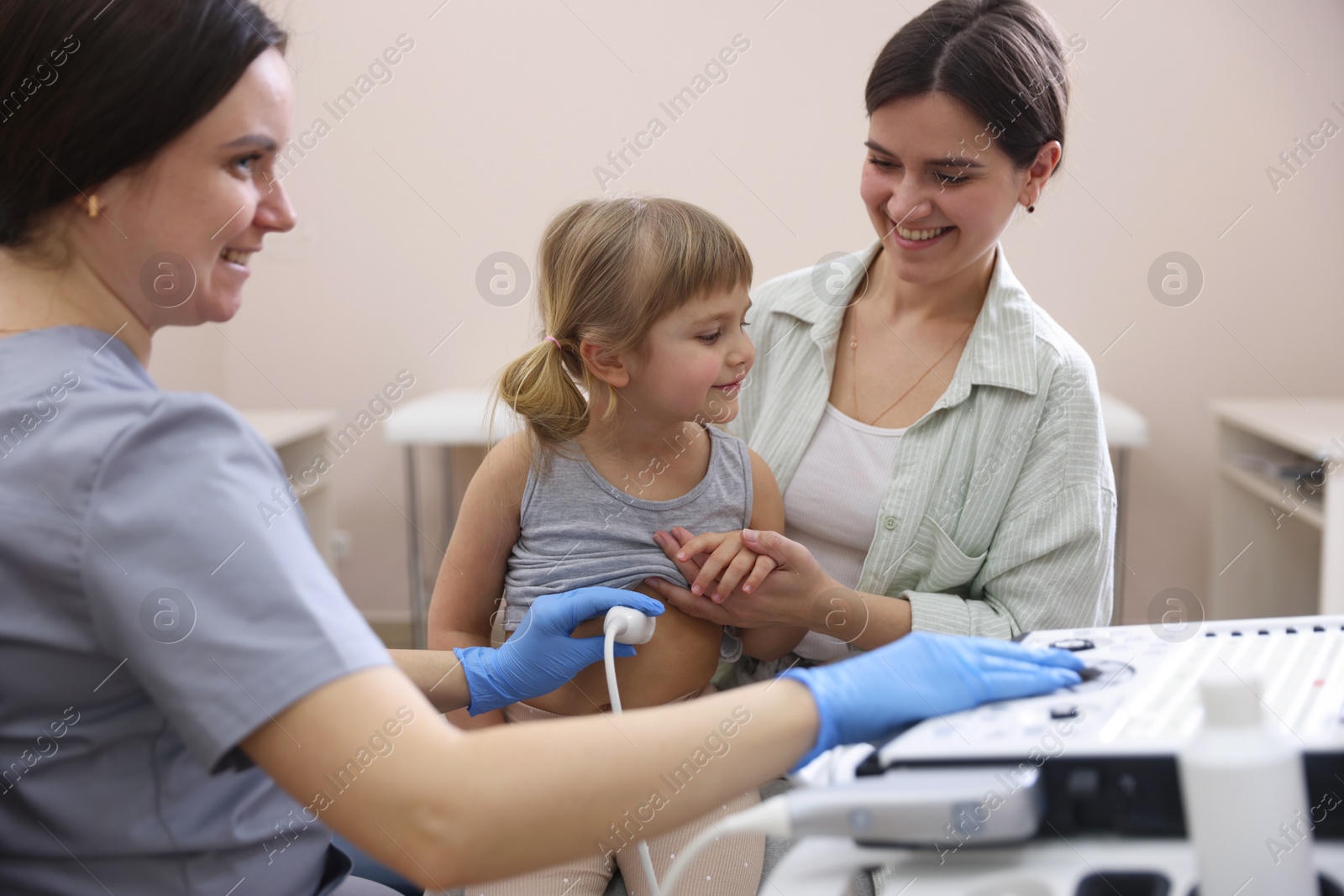 Sonographer conducting little girl's abdominal ultrasound examination. Mother and daughter having appointment with doctor in clinic Photo of Sonographer conducting little girl's abdominal ultrasound examination. Mother and daughter having appointment with doctor in clinic