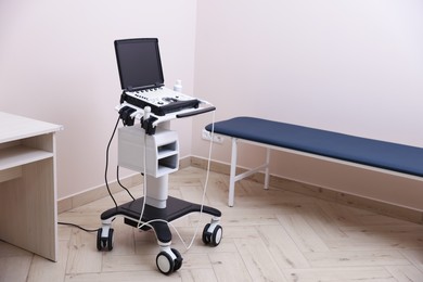 Photo of Modern ultrasound machine and examination bed in clinic