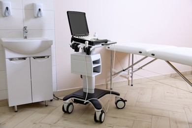 Photo of Modern ultrasound machine, sink and examination bed in clinic