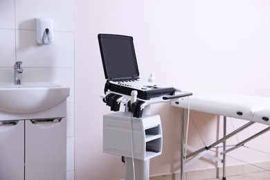 Photo of Modern ultrasound machine, sink and examination bed in clinic