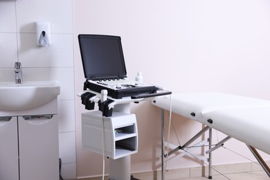 Photo of Modern ultrasound machine, sink and examination bed in clinic