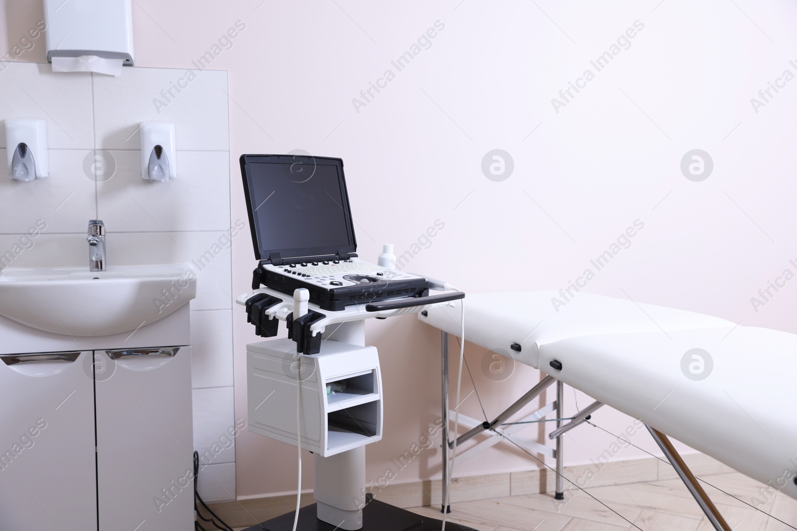 Modern ultrasound machine, sink and examination bed in clinic Photo of Modern ultrasound machine, sink and examination bed in clinic