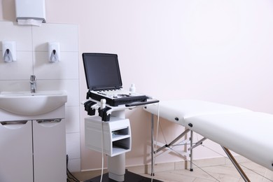 Photo of Modern ultrasound machine, sink and examination bed in clinic