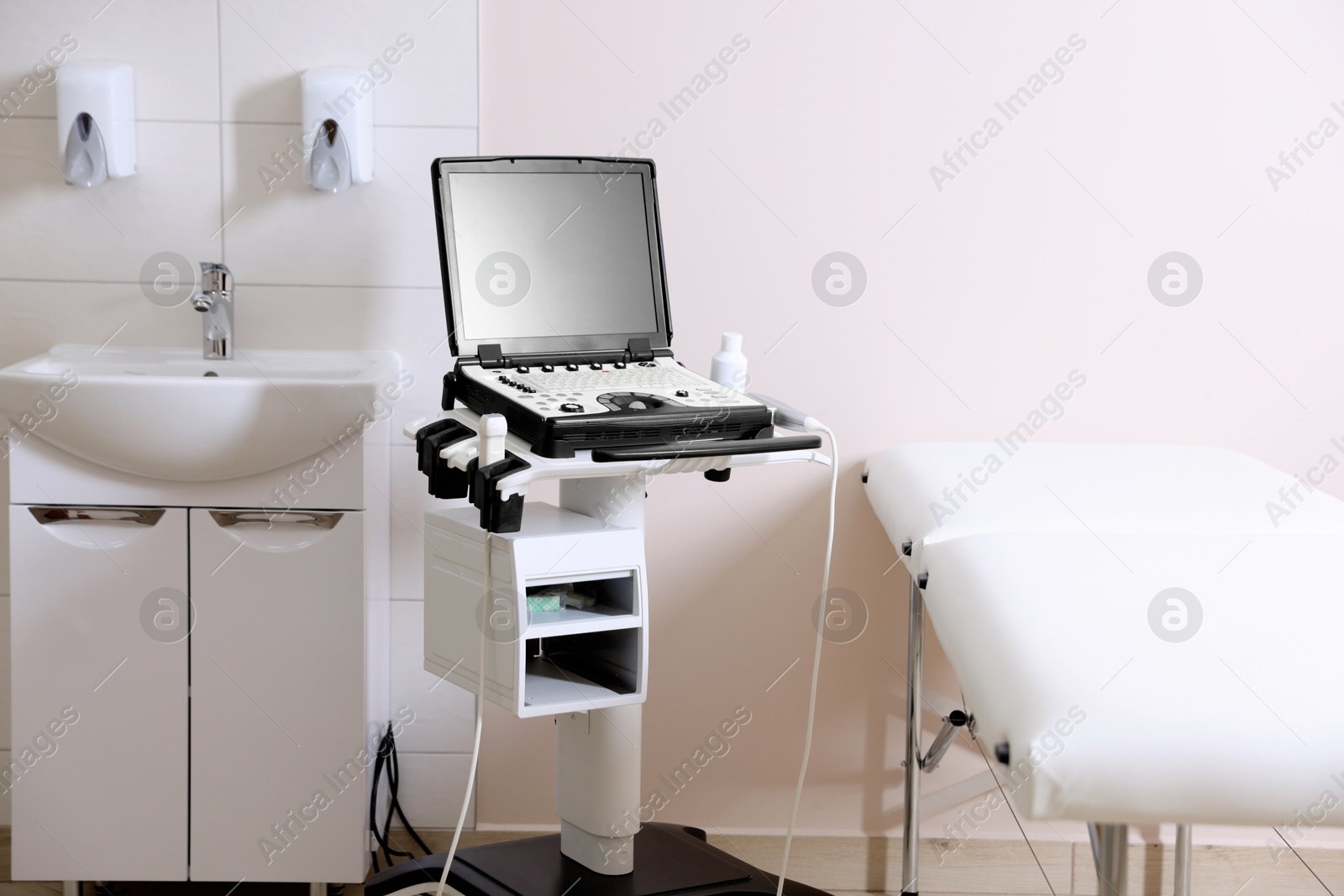Modern ultrasound machine, sink and examination bed in clinic Photo of Modern ultrasound machine, sink and examination bed in clinic