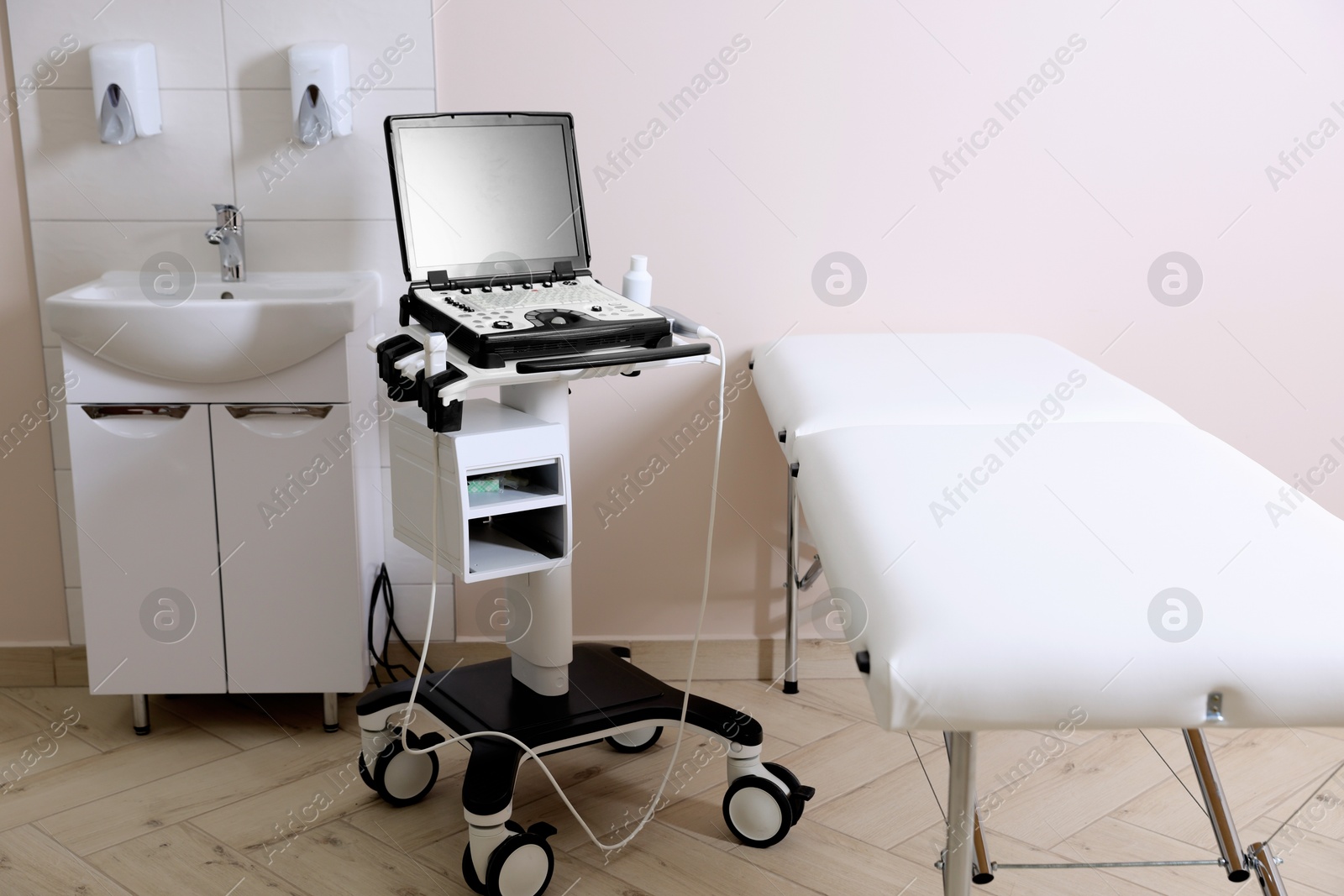 Modern ultrasound machine, sink and examination bed in clinic Photo of Modern ultrasound machine, sink and examination bed in clinic