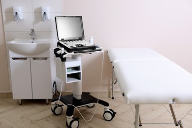 Photo of Modern ultrasound machine, sink and examination bed in clinic