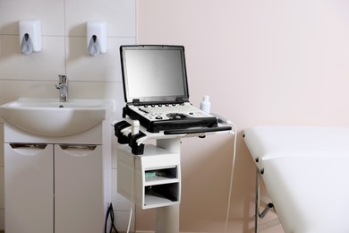 Photo of Modern ultrasound machine, sink and examination bed in clinic