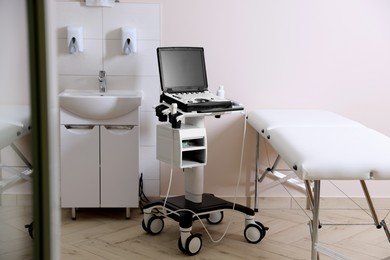 Photo of Modern ultrasound machine, sink and examination bed in clinic