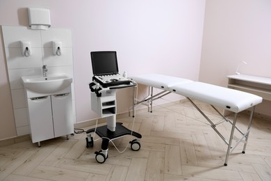 Photo of Modern ultrasound machine, sink and examination bed in clinic