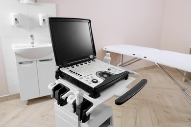 Photo of Modern ultrasound machine and examination bed in clinic