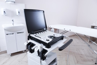 Photo of Modern ultrasound machine and examination bed in clinic