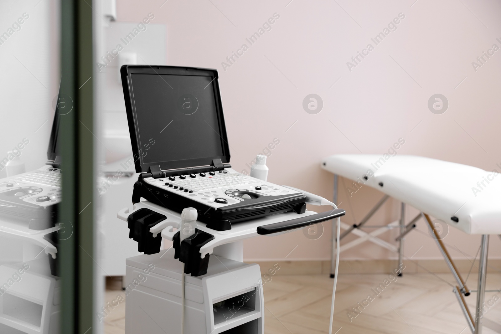 Modern ultrasound machine and examination bed in clinic Photo of Modern ultrasound machine and examination bed in clinic