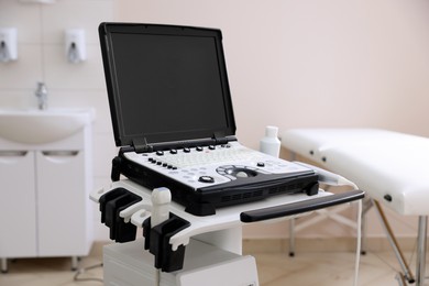 Photo of Modern ultrasound machine and examination bed in clinic