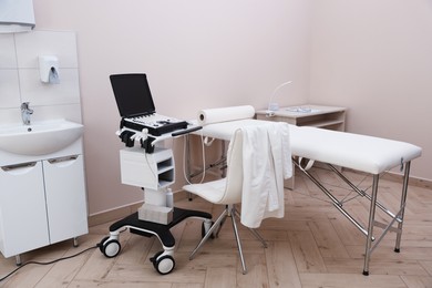 Photo of Modern ultrasound machine and examination bed in clinic