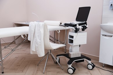 Photo of Modern ultrasound machine and examination bed in clinic