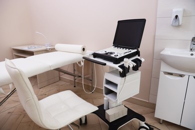 Photo of Modern ultrasound machine and examination bed in clinic