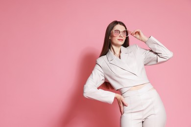Photo of Fashionable portrait of beautiful woman in stylish outfit on pink background. Space for text