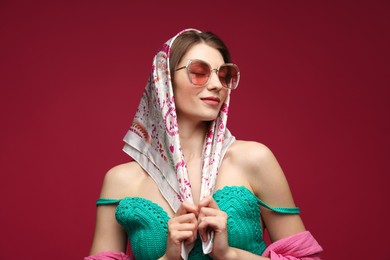Photo of Fashionable portrait of beautiful woman in stylish outfit on dark red background