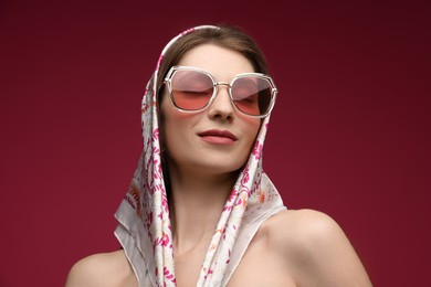 Photo of Fashionable portrait of beautiful woman in stylish outfit on dark red background