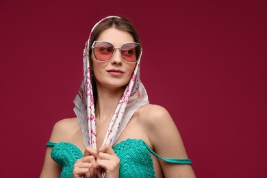 Photo of Fashionable portrait of beautiful woman in stylish outfit on dark red background. Space for text