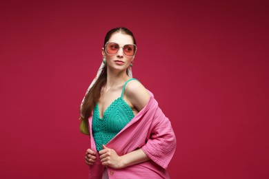Photo of Fashionable portrait of beautiful woman in stylish outfit on dark red background. Space for text