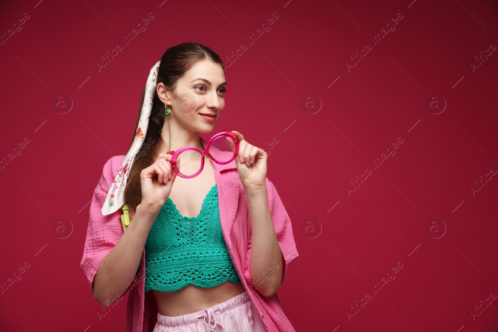 Fashionable portrait of beautiful woman in stylish outfit on dark red background. Space for text Photo of Fashionable portrait of beautiful woman in stylish outfit on dark red background. Space for text