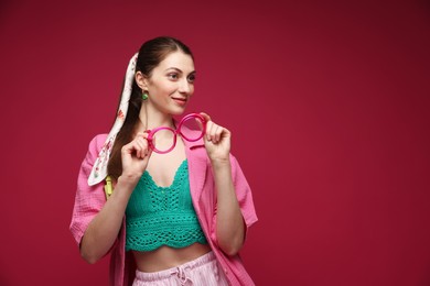 Photo of Fashionable portrait of beautiful woman in stylish outfit on dark red background. Space for text