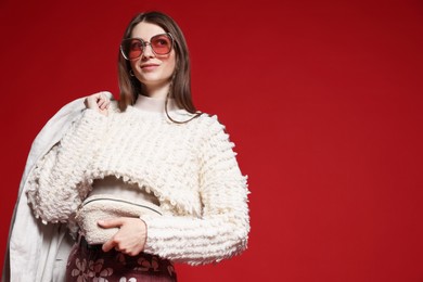 Photo of Fashionable portrait of beautiful woman in stylish outfit on red background. Space for text