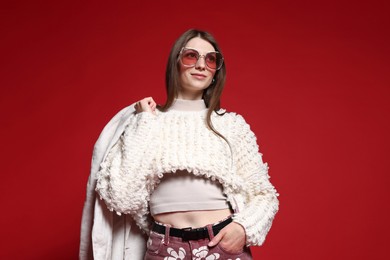 Photo of Fashionable portrait of beautiful woman in stylish outfit on red background