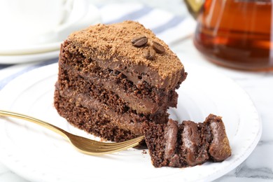 Photo of Piece of delicious chocolate cake with coffee beans and fork on white marble table, closeup