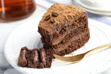 Photo of Piece of delicious chocolate cake with coffee beans and fork on white marble table, closeup