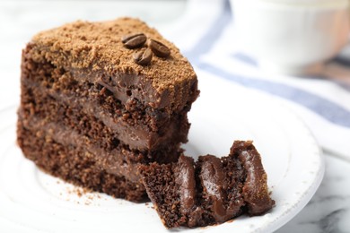 Photo of Piece of delicious chocolate cake with coffee beans on white marble table, closeup