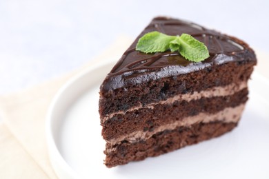 Photo of Piece of delicious chocolate cake with mint on light table, closeup