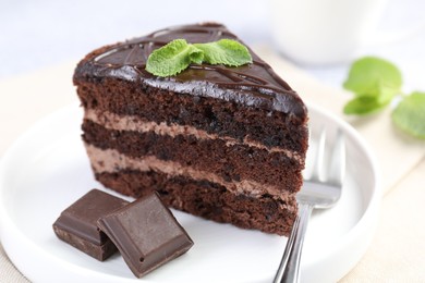 Photo of Piece of delicious cake, mint, chocolate and fork on light table, closeup