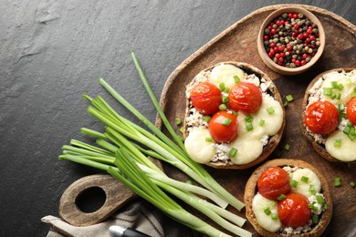 Photo of Tasty stuffed mushrooms served on black table, top view. Space for text