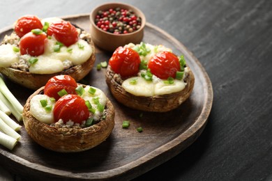 Photo of Tasty stuffed mushrooms served on black table, closeup
