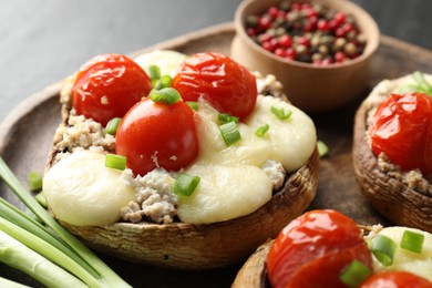 Photo of Tasty stuffed mushrooms served on black table, closeup