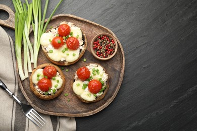Photo of Tasty stuffed mushrooms served on black table, flat lay. Space for text