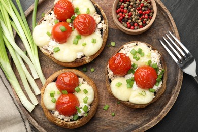 Photo of Tasty stuffed mushrooms served on black table, flat lay