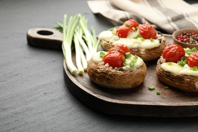Photo of Tasty stuffed mushrooms served on black table, closeup