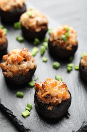 Photo of Tasty stuffed mushrooms served on black table, closeup