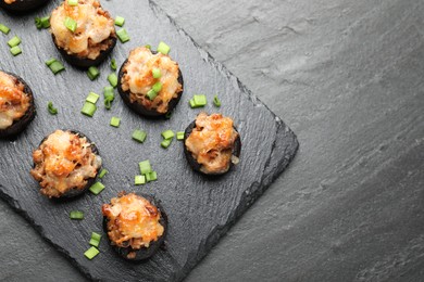 Photo of Tasty stuffed mushrooms served on black table, top view. Space for text