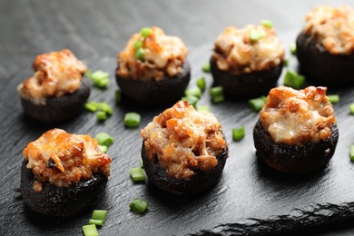 Photo of Tasty stuffed mushrooms served on black table, closeup