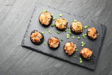Photo of Tasty stuffed mushrooms served on black table, top view