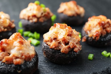 Photo of Tasty stuffed mushrooms served on black table, closeup