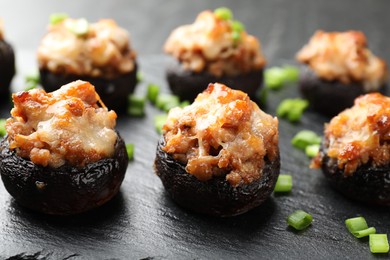 Photo of Tasty stuffed mushrooms served on black table, closeup