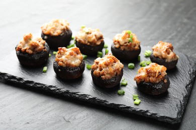 Photo of Tasty stuffed mushrooms served on black table, closeup