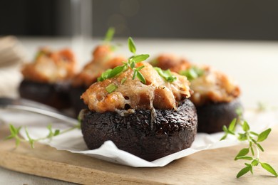Photo of Tasty stuffed mushrooms served on light table against blurred background, closeup