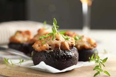 Photo of Tasty stuffed mushrooms served on light table against blurred background, closeup