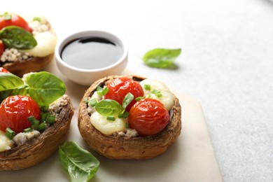 Photo of Tasty stuffed mushrooms served on light table, closeup